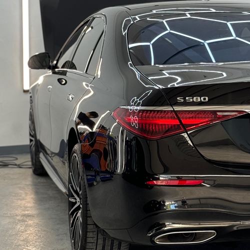 Tył czarnego Mercedesa S 580 w studiu, lakier odbija heksagonalne oświetlenie